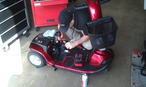 Original client-site photograph of a technician working on a red mobility scooter
